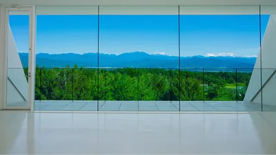 体験ルームの大きなガラス窓ごしに、緑の林と南アルプスの稜線が広がる